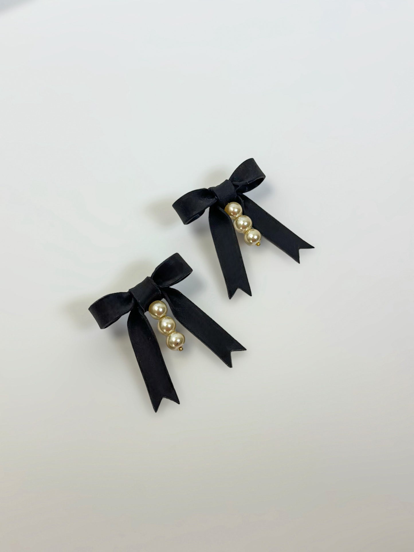 Handmade earrings feature striking black bows that are hand-sculpted and accented with three delicate glass pearls in the center. Hypoallergenic earrings.