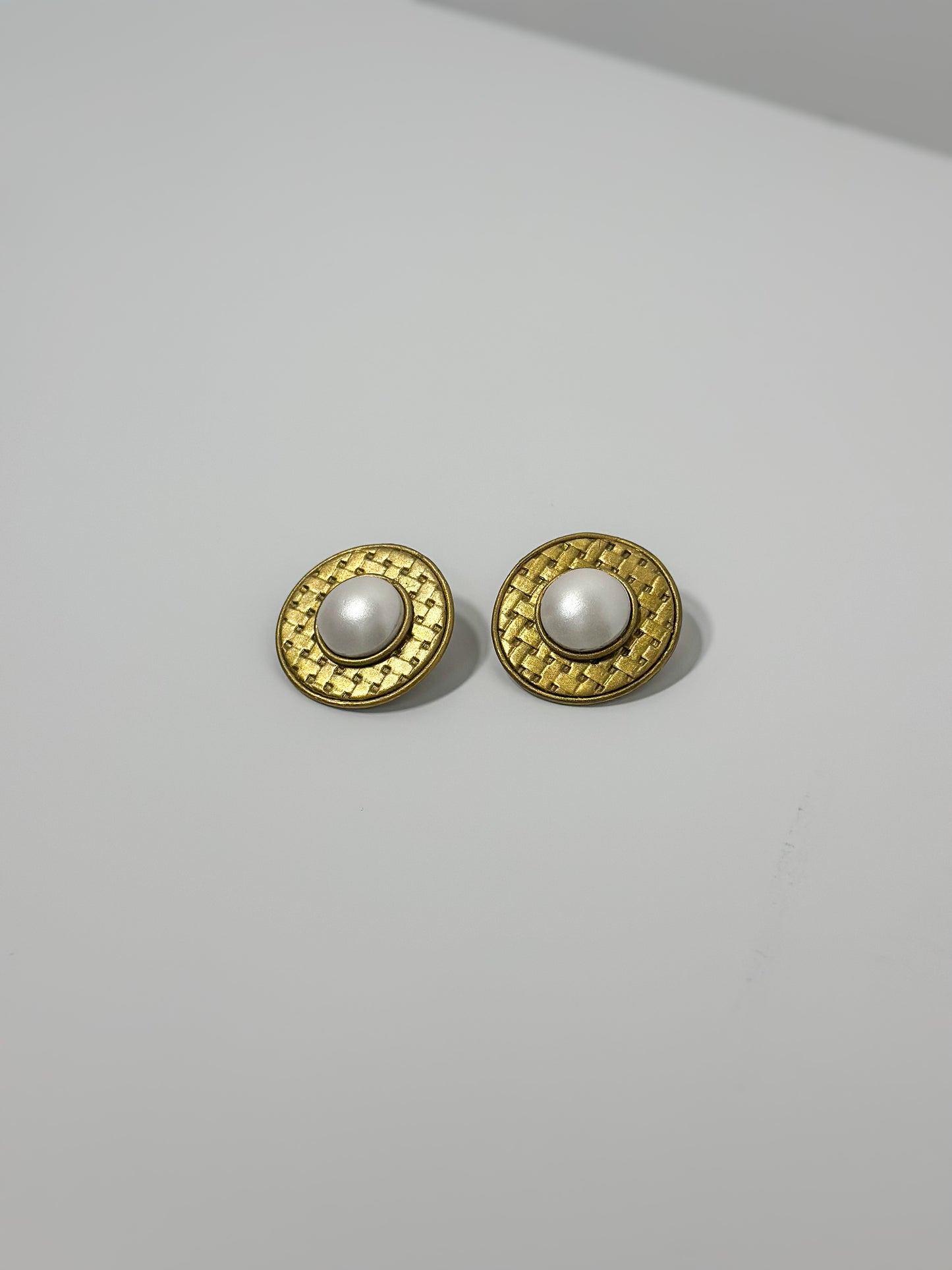 Front Angle: handmade earrings featuring artfully sculpted clay to resemble a central pearl encircled by bold, textured gold details.