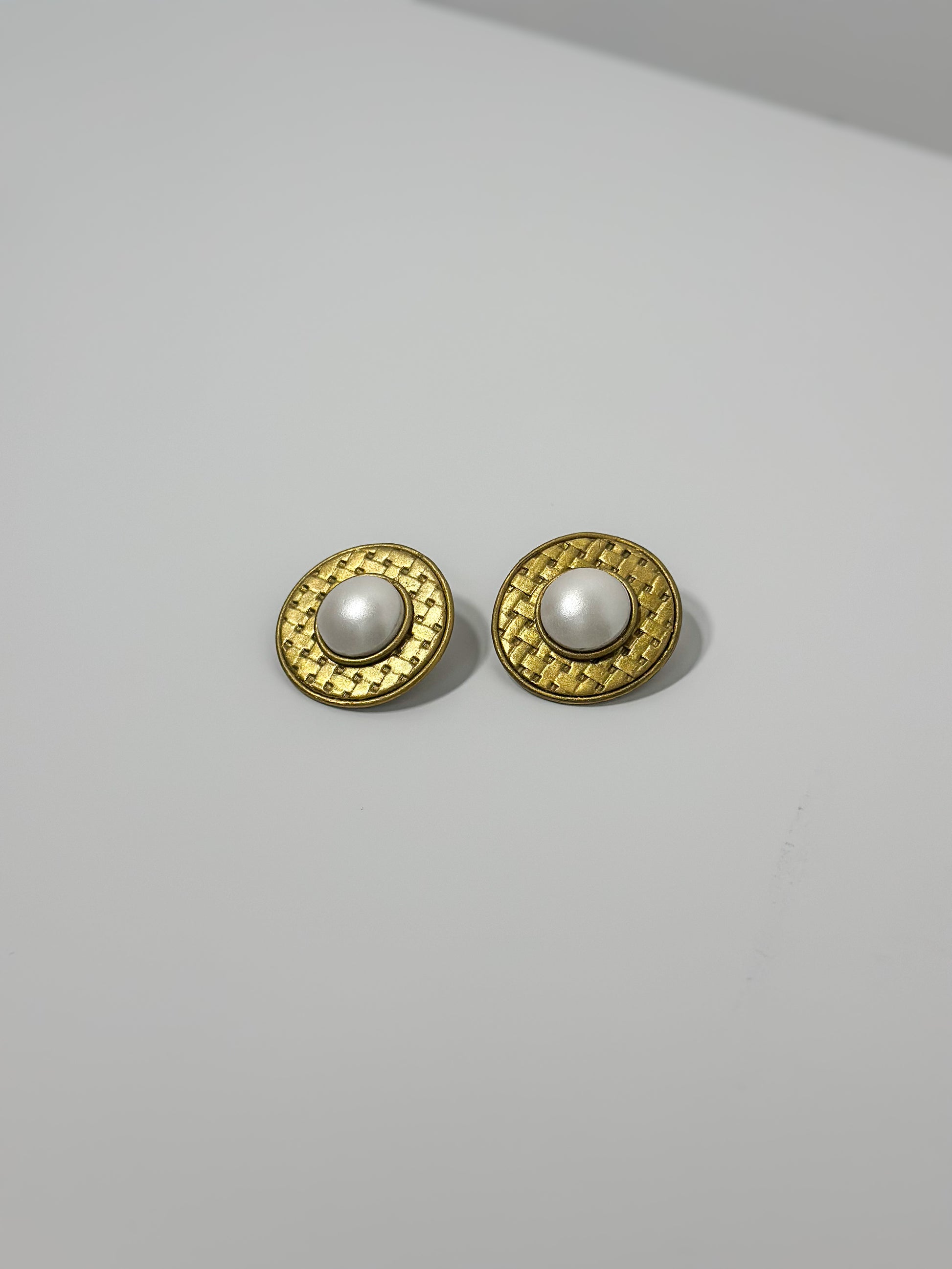 Front Angle: handmade earrings featuring artfully sculpted clay to resemble a central pearl encircled by bold, textured gold details.