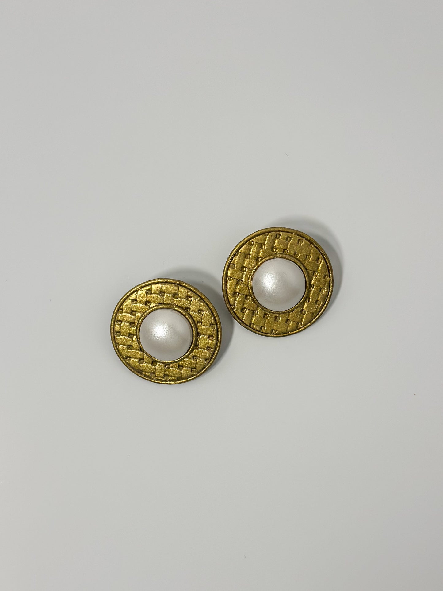 Top Down Angle: handmade earrings featuring artfully sculpted clay to resemble a central pearl encircled by bold, textured gold details.