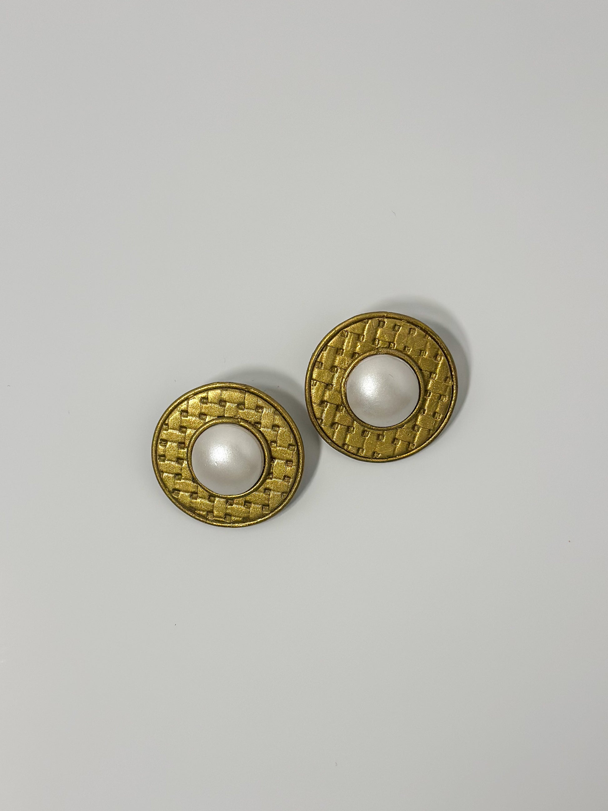 Top Down Angle: handmade earrings featuring artfully sculpted clay to resemble a central pearl encircled by bold, textured gold details.