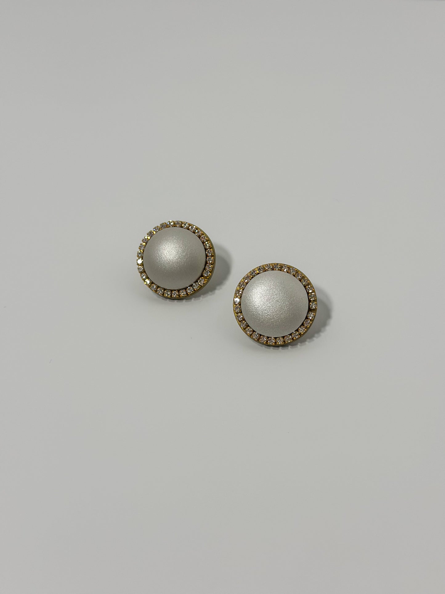 Artfully sculpted clay mimics a pearl in the center, surrounded by sparkling glass rhinestones to create these beautifully handmade earrings.