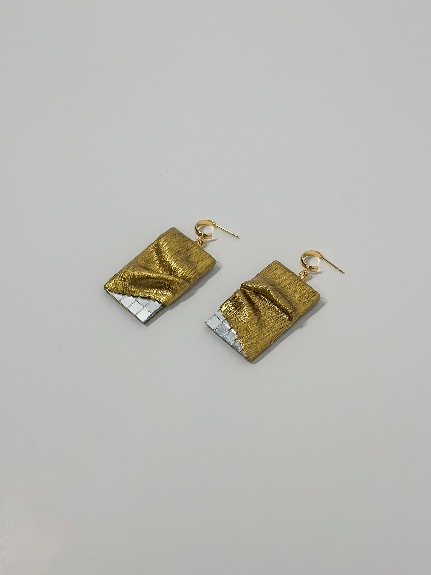 Side View: Crafted from gold clay, these handmade earrings feature intricate sculpting and textured detailing, draping elegantly over glass mirror pieces.