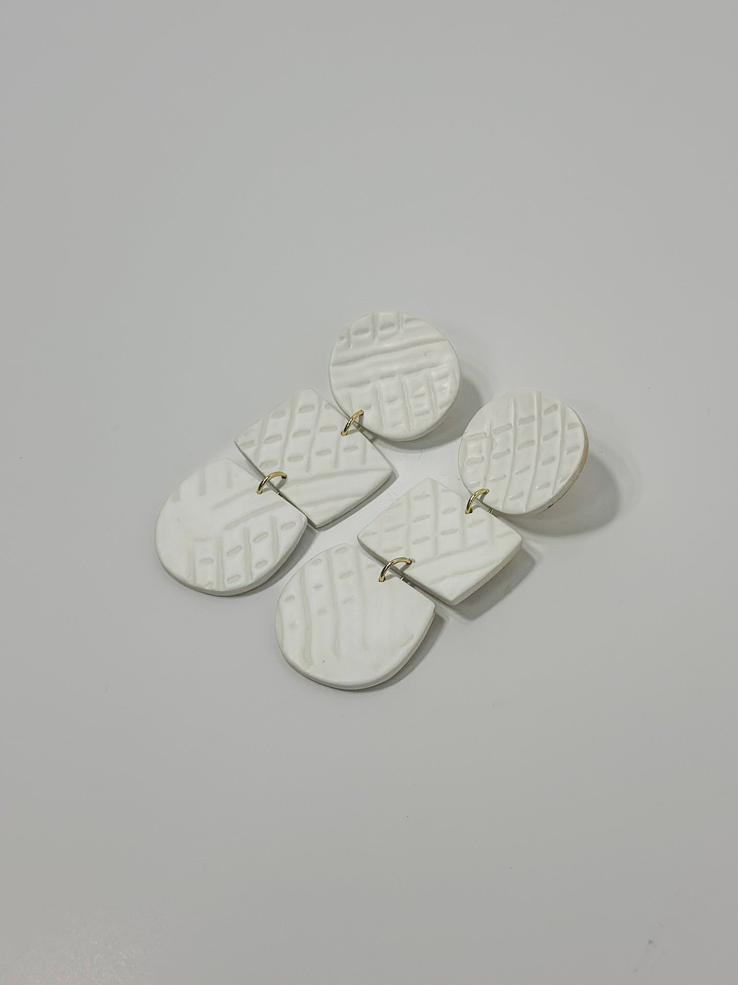 White handmade earrings boast a unique plaster-like texture, offering a chic and minimalist design.